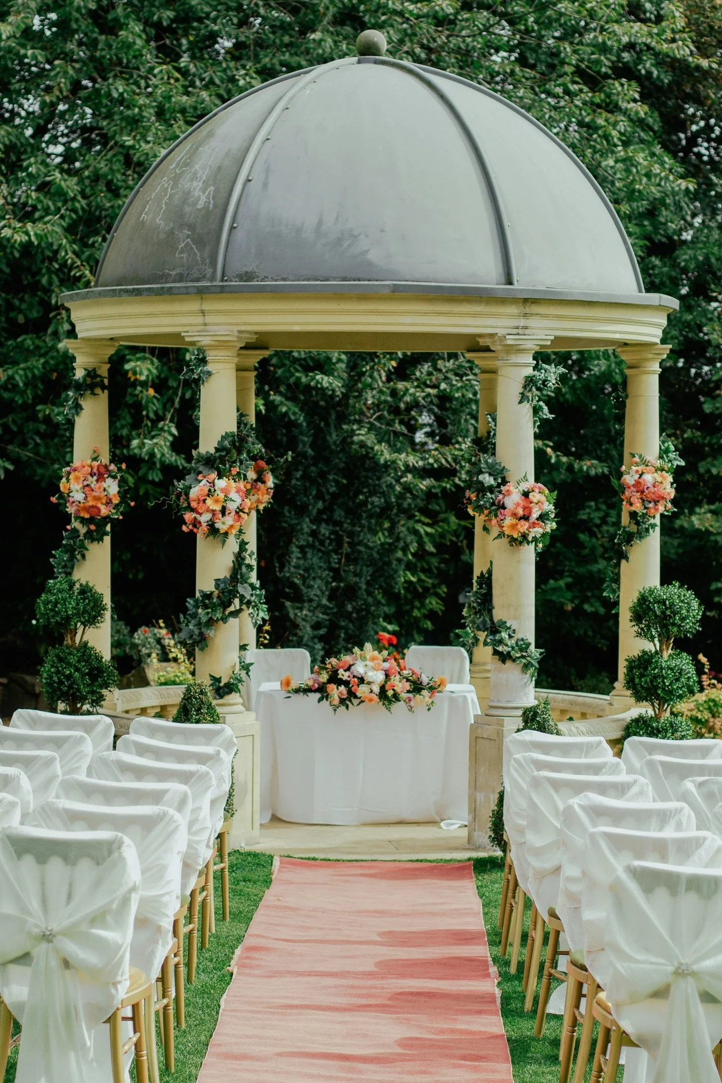 An outdoor wedding ceremony aisle and garden pavilion